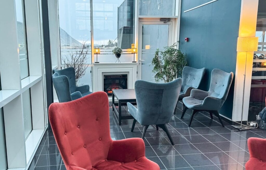 Comfortable blue and red armchairs arranged around a small table in a modern hotel lounge.