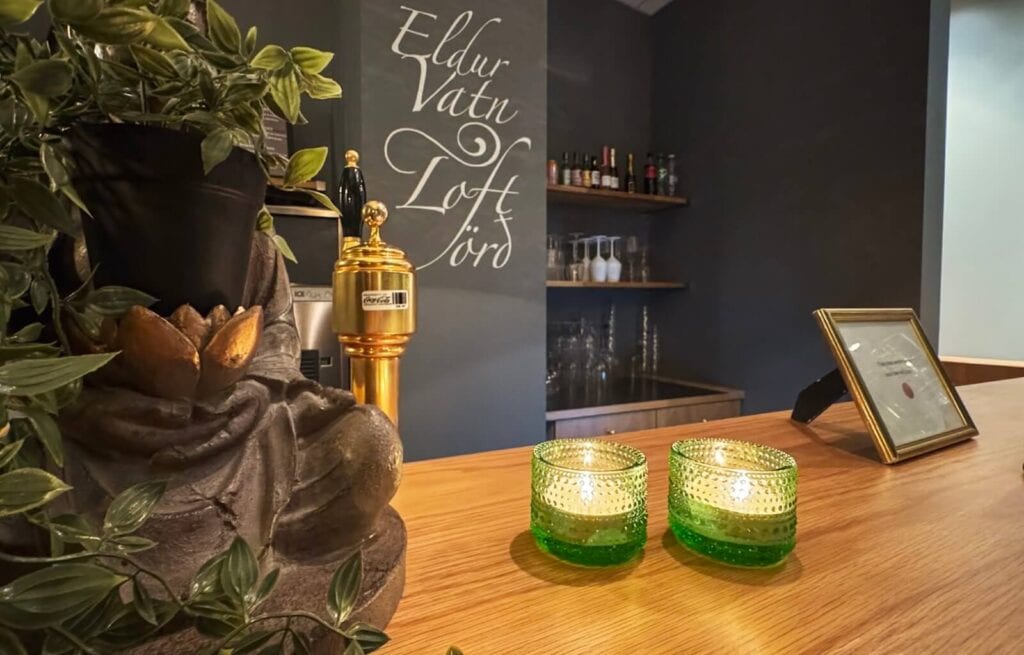 Decorative candles and a plant on a wooden counter in a dimly lit spa or wellness area.