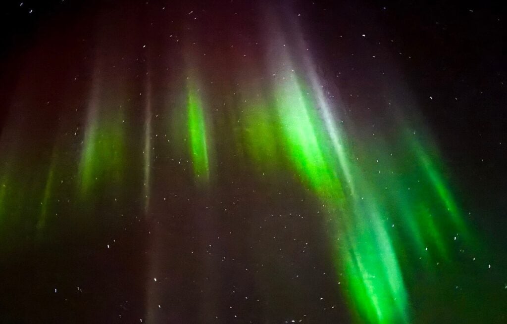 Northern Lights display with green and purple hues in a starry night sky.