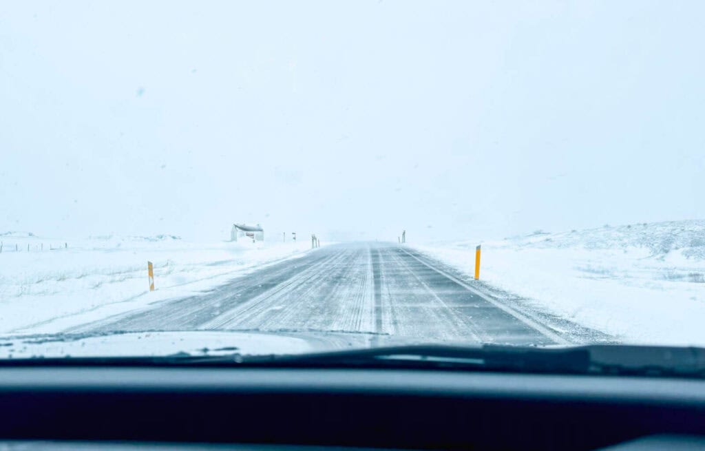 Snow-covered road seen from inside a vehicle during winter in Iceland.
