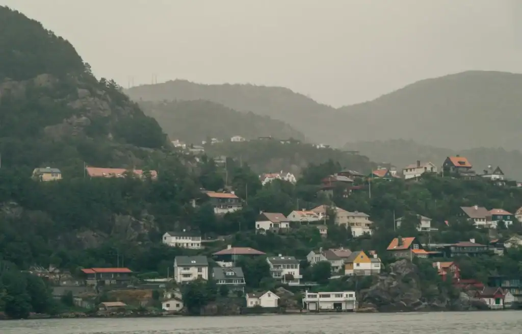 Coastal village with colourful houses on a hillside overlooking the water under cloudy skies.